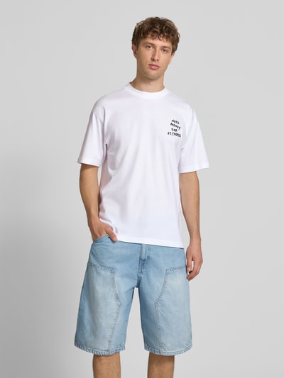 Männermodel trägt Loose Fit T-Shirt aus reiner Baumwolle Modell 'MONEY' von Only & Sons, weiß, Statement-Print, Ganzkörperansicht von vorne