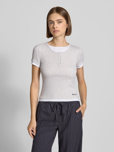 Vrouwenmodel draagt Slim Fit T-Shirt met Logo-Stitching van GUESS Jeans, structuurpatroon, ronde hals, met korte mouwen, ruglengte bij maat S 50 cm, Ganzkörperansicht von vorne.
