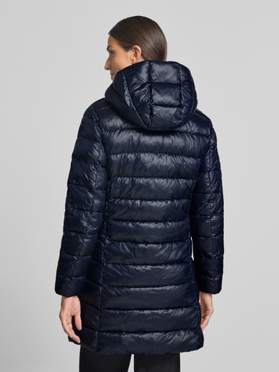 Vrouwenmodel draagt lange jas in stiksels, regular fit, Model 'Adelaide' van Blauer vs, logo-design, capuchon met tunnelkoord, steekzakken met ritssluiting, ruglengte maat S 85 cm, schouderbreedte 40 cm, borstwijdte 48 cm, mouwlengte 62 cm, donkerblauw, Ganzkörperansicht Rückansicht.