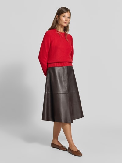 Frauenmodel trägt Midirock aus echtem Lammnappa von MYON, A-Linie, Ziernähte, Nahtreißverschluss, schwarzer Leder-Look, Ganzkörperansicht von vorne.