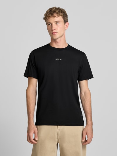 Männermodel trägt T-Shirt mit Rundhalsausschnitt und Logo von Replay in Schwarz, Slim Fit, reine Baumwolle, Ganzkörperansicht von vorne.