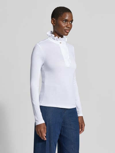 Modelka nosi Longsleeve mit Rüschen von Rich & Royal z mieszanki lyocellu i bawełny, taliowany krój, kołnierz z ukrytą listwą guzikową, falbany, długość tyłu w rozmiarze 36: 60 cm, biel, gładka tekstura, widok całej sylwetki z przodu
