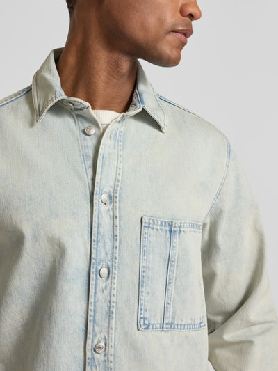 Männermodel trägt Regular Fit Jeanshemd mit Brusttasche Modell 'DAMON' von Samsøe Samsøe aus reiner Baumwolle, Nahaufnahme Oberkörper.