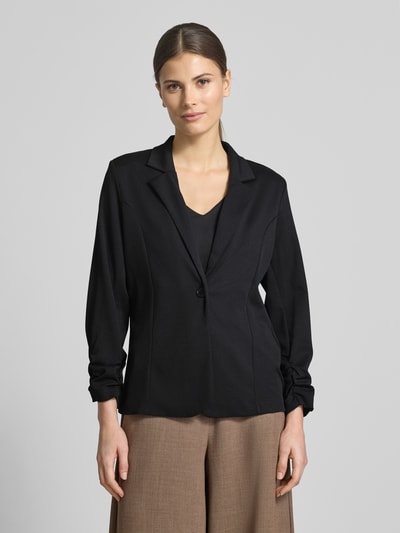 Frauenmodel trägt schwarzen Blazer mit Raffungen Modell 'Siham' von Soyaconcept, Elastischer-Material-Mix, Taillierte Passform, Reverskragen, Knopfverschluss, Rückenlänge 58 cm, Brustweite 50 cm, Ärmellänge 54 cm, Ganzkörperansicht von vorne.
