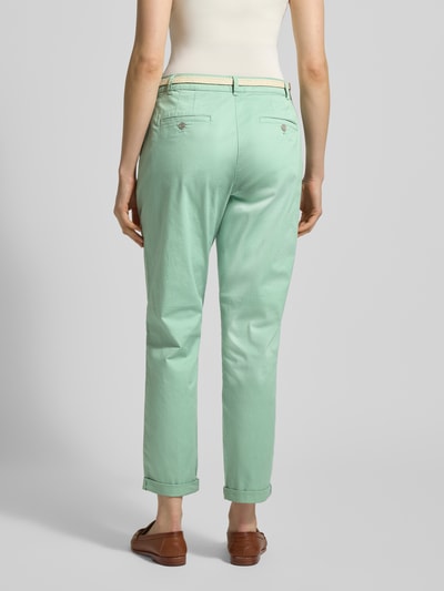 Modelka nosi Casual Fit Chino mit Baumwoll-Anteil od Christian Berg Woman, miękka zielona mieszanka bawełny, pasek, skrócony krój, szerokość w rozmiarze 36: 41 cm, długość wewnętrzna nogawki: 70 cm, widok całej sylwetki z tyłu