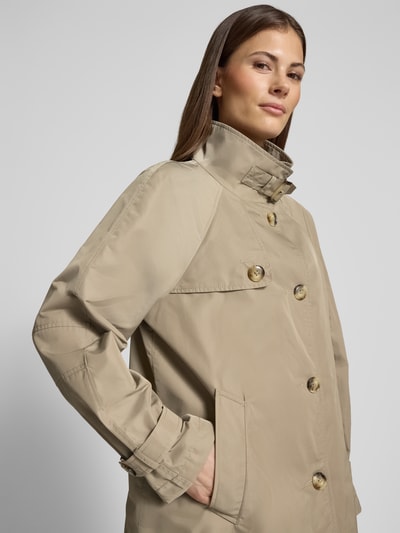Modelka kobieca nosi Trenchcoat mit Stehkragen und Ärmelriegeln od Fuchs Schmitt, beżowy, krój relaxed fit, zapięcie na guziki, kieszenie, detal rękawa, Szerokość w rozmiarze 36: 54 cm, długość tyłu: 72 cm, szerokość ramion: 40 cm, długość rękawa: 60 cm, zbliżenie na górną część sylwetki, widok z przodu.