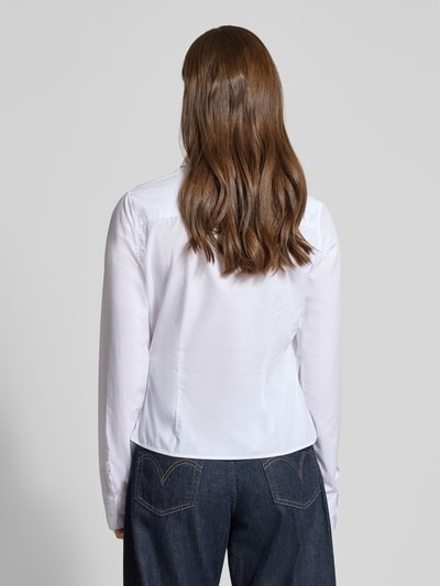 Frauenmodel trägt Slim Fit Bluse mit Knopfleiste von Guess Jeans, weiße Baumwolle, Hemdblusenkragen, Rückenlänge 55 cm, Ganzkörperansicht Rückansicht.