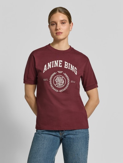 Vrouwenmodel draagt bordeauxrood T-Shirt met Label-Print van Anine Bing, rechte fit, ronde hals, katoen, detailopname bovenlichaam.