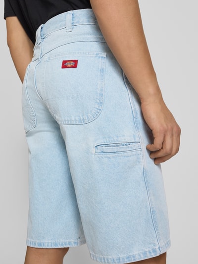 Männermodel trägt Loose Fit Bermudas mit Eingrifftaschen von Dickies aus Reine Baumwolle, Denim in Hellblau, Ganzkörperansicht Rückansicht.