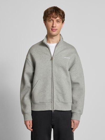 Männermodel trägt graue Sweatjacke mit Stehkragen von Carhartt Work In Progress, lockerer Schnitt, Reißverschluss, Ganzkörperansicht von vorne.
