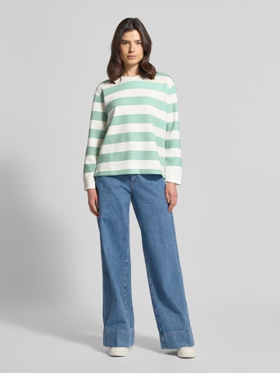 Frauenmodel trägt Sweatshirt mit Rundhalsausschnitt von Christian Berg Woman im Allover-Look, Material-Mix mit Modal-Anteil, Relaxed-Fit, mintgrün-weiße Streifen, lockere Passform, weiche Struktur, kombiniert mit weiter Jeans, Ganzkörperansicht von vorne.