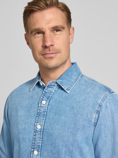 Männermodel trägt Regular Fit Jeanshemd mit Kentkragen von Gant aus Reine Baumwolle, hellblaue Farbe, Nahaufnahme Oberkörper.
