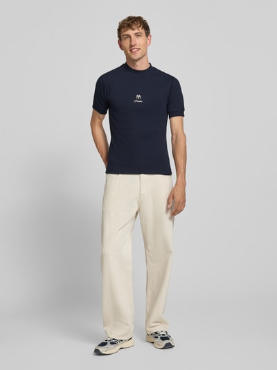 Męski model nosi Slim Fit T-Shirt mit Label-Stitching von PROHIBITED, mieszanka bawełny i elastanu, efekt prążkowania, okrągły dekolt, długość tyłu przy rozmiarze M: 64 cm, krój slim fit, granatowy kolor, gładka tekstura, pełny widok z przodu.