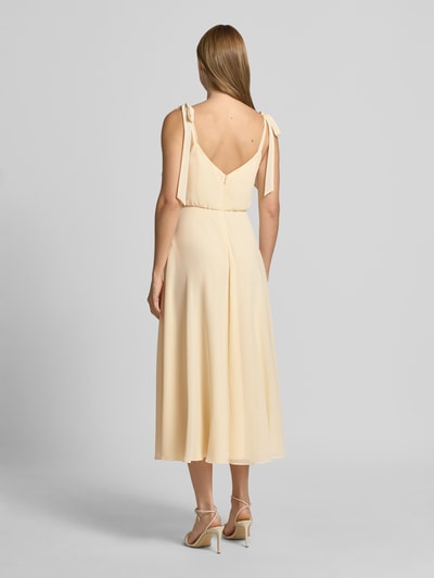 Frauenmodel trägt Knielanges Cocktailkleid mit Zierschleifen von Jake*s Cocktail, cremefarben, blickdichter Unterrock, taillierte Passform, knielang, Ärmelloses-Design, Rückenlänge 97 cm bei Größe 36, Brustweite 33 cm, Ganzkörperansicht Rückansicht.