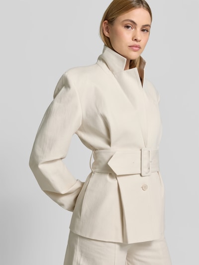 Frauenmodel trägt Blazer aus Leinen-Mix mit Taillen-Gürtel von ROTATE, cremefarben, Reverskragen, Knopfleiste, Brusttasche, taillierte Passform, Ganzkörperansicht von vorne. Kontext: Rückenlänge bei Größe 36: 69 cm, Brustweite: 41 cm, Ärmellänge: 69 cm, Taillenweite: 31 cm.