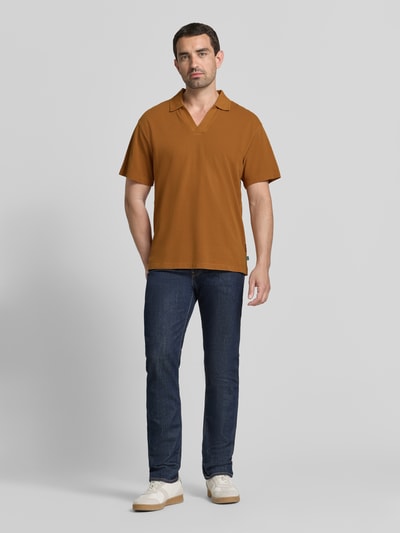 Männermodel trägt Relaxed Fit Poloshirt in Pique-Optik von Scotch & Soda, Reine Baumwolle, Kurzärmelig, Polokragen, Ganzkörperansicht von vorne.