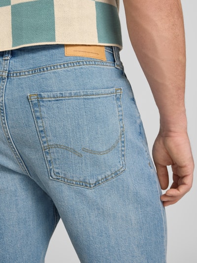 Männermodel trägt Relaxed Fit Jeansshorts Modell 'TONY' von Jack & Jones aus Baumwoll-Elasthan-Mix mit Eingrifftaschen, Nahaufnahme Rückansicht. Bundweite 42 cm, Innenbeinlänge 21 cm, Farbe Hellblau, grobe Textur.