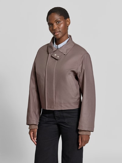 Frauenmodel trägt Jacke aus reiner Baumwolle von Victoria Beckham in Taupe, Regular Fit, Stehkragen, elastische Ärmelabschlüsse, Ganzkörperansicht von vorne.