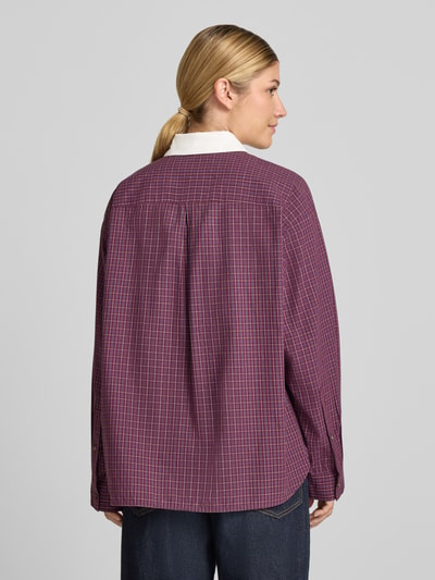 Frauenmodel trägt Oversized Langarmbluse aus reiner Baumwolle von Jake*s Casual, kariertes Muster in Violett und Weiß, Rückansicht.