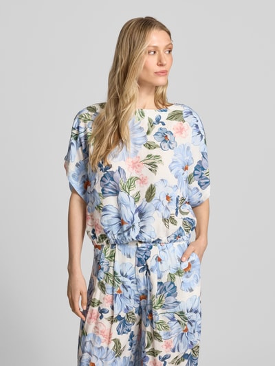 Frauenmodel trägt Bluse aus Viskose-Mix mit U-Boot-Ausschnitt von Oui, floraler Print in Blau und Rosa, Gerader-Schnitt, Fledermausärmel, elastischer Saumabschluss, Leinen-Viskose-Anteil, Rückenlänge bei Größe 36: 48 cm, Nahaufnahme Oberkörper.