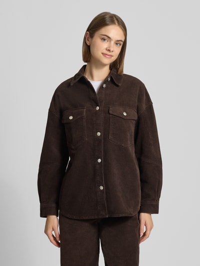 Frauenmodel trägt Loose Fit Hemdjacke aus reiner Baumwolle Modell 'TIGGY' von ONLY in brauner Cordoptik mit Brusttaschen, Ganzkörperansicht von vorne.