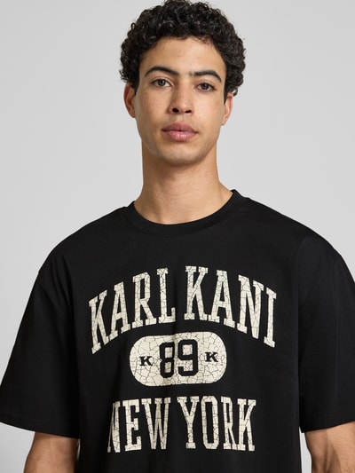 Männermodel trägt Oversized Fit Herren T-Shirt von KARL KANI aus Reine Baumwolle mit Logo-Print Modell 'Heritage', Rundhalsausschnitt, Nahaufnahme Oberkörper.
