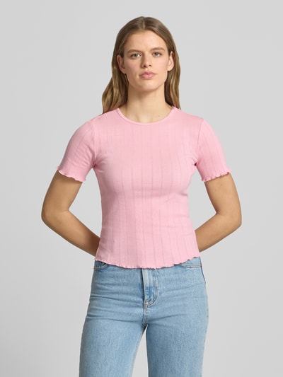 Frauenmodel trägt Slim Fit T-Shirt aus Baumwoll-Mix Modell 'TENNA' von Only in Optik: Unifarben, Rundhals, Kurzarm, Frill-Abschlüsse, Material: Baumwoll-Mix, zartes Rosa, feine Rippenstruktur, Ganzkörperansicht von vorne.