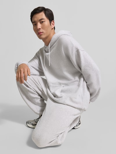 Männermodel trägt Hoodie mit Känguru-Tasche Modell 'ATUBAY' von American Vintage in Hellgrau, Baumwoll-Elasthan-Mix, Relaxed-Fit, Ganzkörperansicht von vorne.