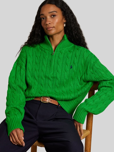 Frauenmodel trägt Troyer mit Zopfstrickmuster von Polo Ralph Lauren in kräftigem Grün, reine Baumwolle, Logo-Stitching, Nahaufnahme Oberkörper.