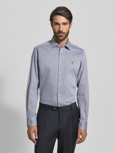 Männermodel trägt Regular Fit Businesshemd aus reiner Baumwolle von Tommy Hilfiger, unifarben, Kentkragen, Ganzkörperansicht von vorne.