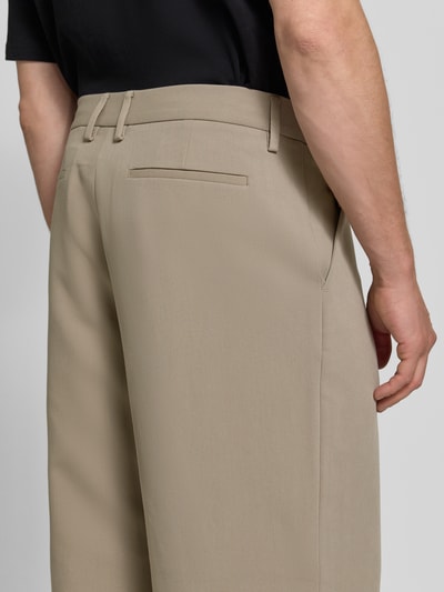 Männermodel trägt Wide Leg Bundfaltenhose mit Viskose-Anteil von Jake*s, unifarben, matt, feines Webmuster, Ganzkörperansicht Rückansicht.