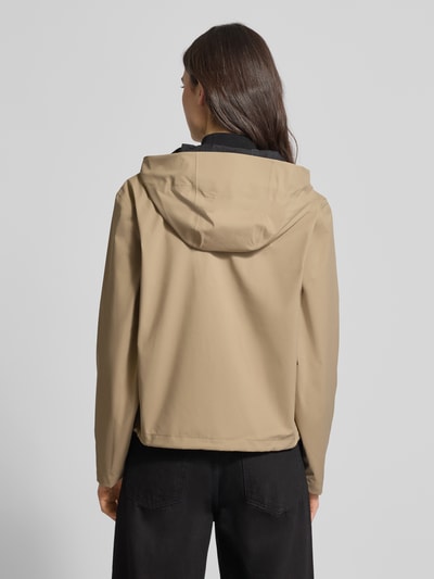 Frauenmodel trägt beigetönige Regular Fit Jacke mit Kapuze Modell 'Suva' von Rains, glatte Textur, Rückenansicht, Kontext: Damen Jacke mit Tunnelzug, Zweiwege-Reißverschluss, Bund mit Tunnelzug, Rückenlänge 59 cm, Schulterbreite 49 cm, Brustweite 54 cm, Ärmellänge 60 cm.