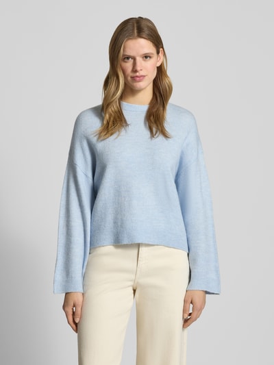 Frauenmodel trägt Relaxed Fit Strickpullover mit Crew Neck Modell 'SIMONI' von Only in Melange-Optik, hellblau, Rundhals, gerippte Abschlüsse, Strickmaterial, Ganzkörperansicht von vorne.
