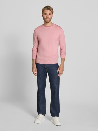 Männermodel trägt Regular Fit Wollpullover von Paul Smith in Rosa, reine Wolle, Strick, Rundhalsausschnitt, Jeans, Ganzkörperansicht von vorne.