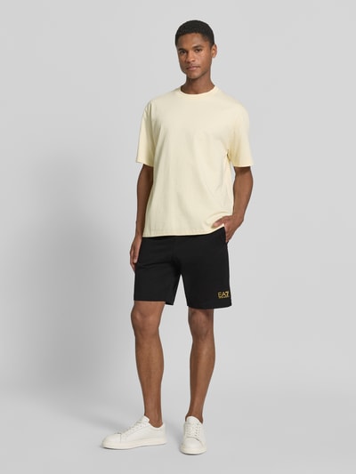 Männermodel trägt Shorts mit elastischem Bund und Logo von EA7 Emporio Armani aus Reine Baumwolle, Regular-Fit, Logo, Ganzkörperansicht von vorne.