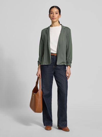 Kobieta modelka nosi Blazer mit Raffungen Modell 'Siham' od Soyaconcept, zielony, taliowany, elastyczny materiał, długość tyłu 58 cm, szerokość w rozmiarze S 50 cm, długość rękawa 54 cm, zapięcie na guzik, klapy, widok całej sylwetki z przodu.
