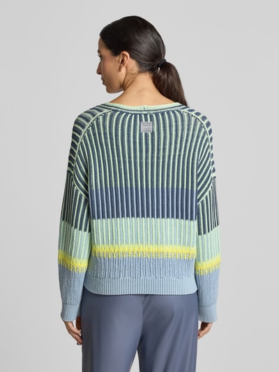 Frauenmodel trägt Oversized Strickpullover mit V-Ausschnitt von Marc Cain, gestreiftes Design in Blau, Gelb, Baumwoll-Mix, Ganzkörperansicht Rückansicht.
