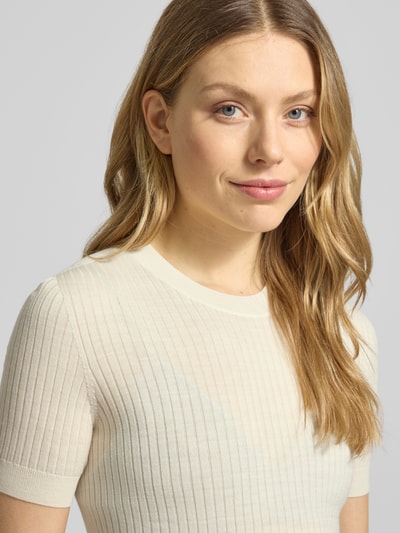 Vrouwenmodel draagt Regular Fit Strick-Shirt aus reiner Wolle van Lacoste, look: effen, pasvorm: regular fit, gestikt logo, ronde hals, korte mouw, mouw- en rompzoom: geribd, materiaalverwerking: fijne ribtricot, materiaal: wol. Nahaufnahme bovenlichaam.