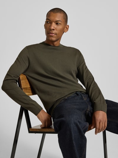 Männermodel trägt Regular Fit Pullover aus reiner Baumwolle Modell 'TORINO' von Selected in Olivgrün, schlichte Struktur, Ganzkörperansicht von vorne, Herren Pullover von Selected.