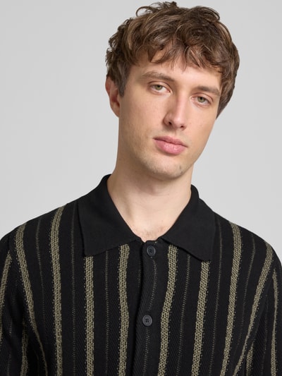 Männermodel trägt Regular Fit Strickjacke aus reiner Baumwolle von Marc O'Polo Denim, schwarz mit beigem Allover-Streifenmuster, Nahaufnahme Oberkörper.