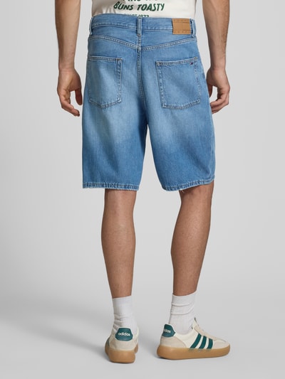 Męski model nosi Relaxed Fit Jeansbermuda aus reiner Baumwolle von Tommy Jeans, jasny denim, krój relaxed fit, wyhaftowane logo, 5 kieszeni, materiał: bawełna, Ganzkörperansicht Rückansicht.
