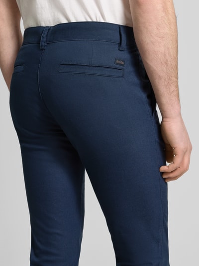 Męski model nosi Slim Fit Chino aus Baumwoll-Mix mit Leinen und Viskose-Anteil Modell 'Chino-Slim-2' od BOSS Orange, tkanina stylizowana na denim, krój slim fit, średni stan, naszywka z logo, zapięcie na guzik i ukryty zamek błyskawiczny, boczne wpuszczane kieszenie i tylne kieszenie, wykończenie materiału: splot twill, mieszanka bawełny, lnu i wiskozy, widok z tyłu, zbliżenie na dolną część pleców.