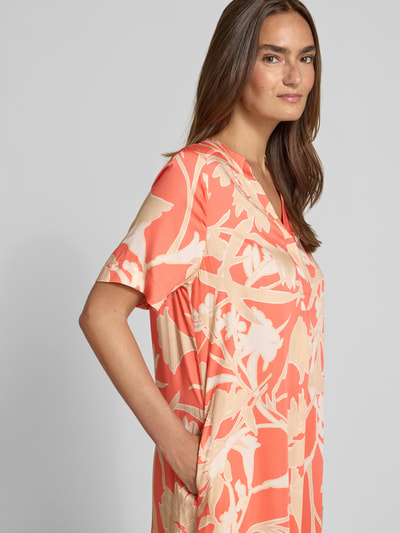 Frauenmodel trägt Knielanges Tunikakleid aus Viskose mit Tunikakragen von Milano Italy in Koralle-Beige mit floralem Muster, Reine Viskose, Straight Fit, Knielänge, Rückenlänge bei Größe 36: 100 cm, Brustweite: 51 cm, Ärmellänge: 24 cm, Nahaufnahme Oberkörper.