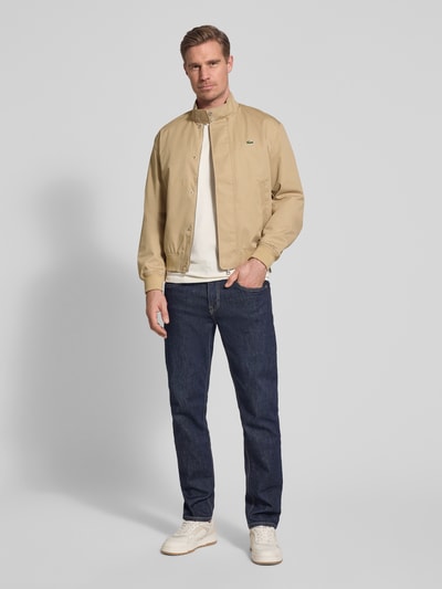 Męski model nosi Regular Fit Bomberka z bawełnianym udziałem Model 'HARRINGTON' od Lacoste, efekt: jednolity kolor, krój regular fit, stójka, zapięcie: kryty zamek błyskawiczny, kryta listwa guzikowa, wyhaftowane logo, prążkowane zakończenia rękawów i dołu, boczne wpuszczane kieszenie, całkowity widok z przodu.