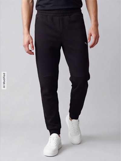 Männermodel trägt schwarze Regular Fit Sweathose aus Baumwoll-Mix Modell 'PUMATECH' von PUMA, Herren Sweathose, Ganzkörperansicht von vorne, KI-modifiziertes Bild.