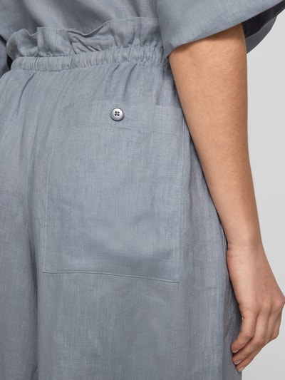Kobieta modelka nosi Wide Leg Leinenhose Modell 'DWINDLE' od Drykorn, czysty len, elastyczny pas, sznur, widoczna kieszeń, zbliżenie tylu.