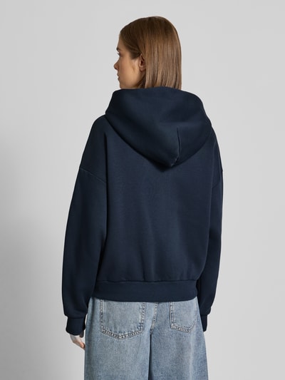 Frauenmodel trägt Relaxed Fit Basic Sweatjacke mit Kapuze von REVIEW, dunkelblau, Baumwoll-Mix, Logo-Print, Rückansicht, Ganzkörperansicht.
