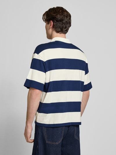 Männermodel trägt Relaxed Fit Poloshirt aus reiner Baumwolle Modell 'DEVIN' von Only & Sons, blau-weiß gestreift, Ganzkörperansicht Rückansicht.