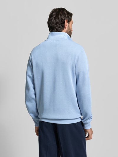 Männermodel trägt Regular Fit Troyer aus reiner Baumwolle von Lacoste in Hellblau, Strick, unifarben, Ganzkörperansicht Rückansicht.