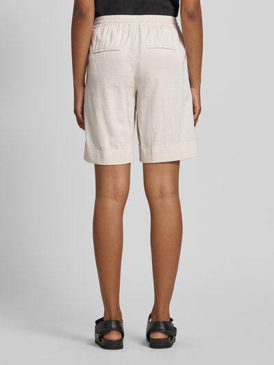Frauenmodel trägt Bermudas mit elastischem Bund und Kordelzug Modell 'Lia Urban' von Angels aus Reine Baumwolle, Loose-Fit, crèmefarben, eingewebte Struktur, mit seitlichen Eingrifftaschen und Gesäßleistentaschen, Ganzkörperansicht Rückansicht.